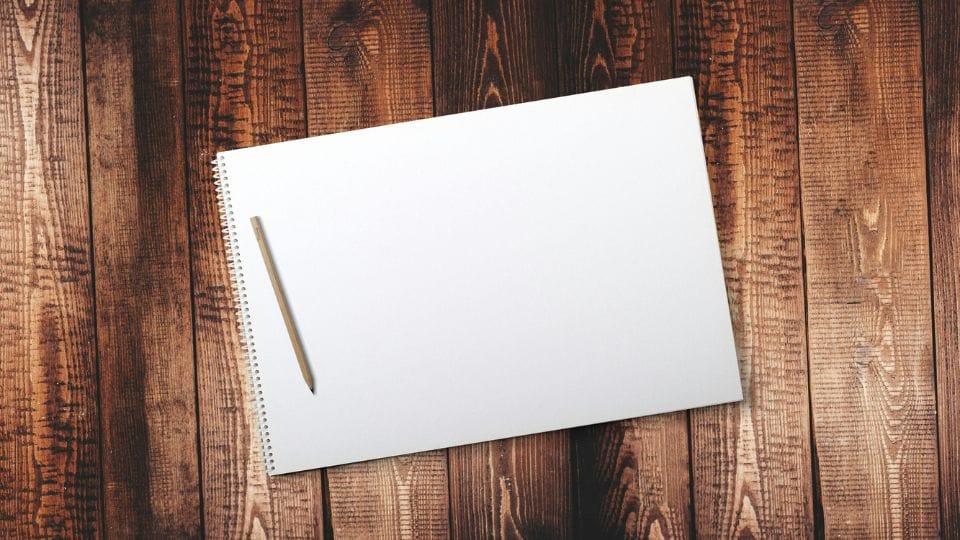 Papel em branco sobre uma mesa, ilustrando o que é o bloqueio criativo no desenho.
